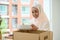 Beautiful asian muslim woman packing her kitchenware into a cardboard box