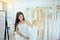 Beautiful asian woman bride trying on white wedding dress in room