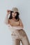 Beautiful asian woman brunette in beige fashionable clothes with hat