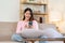 Beautiful Asian woman in casual clothes sitting on sofa using smartphone for social entertainment to relax. smile and laugh