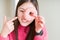 Beautiful Asian woman eating pink sugar donut very happy pointing with hand and finger