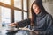 A beautiful asian woman grabbing a coffee cup while reading a book