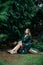 Beautiful asian woman in green dress sit and taking views in the park with green leaves