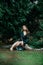 Beautiful asian woman in green dress sit and taking views in the park with green leaves