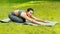 Beautiful Asian woman making child pose on yoga mat at green park