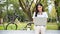 Beautiful Asian woman remote working at the park, using her laptop to manage her tasks