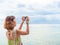 Beautiful asian woman with short hair using smart phone take a photo seascape view