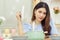 Beautiful Asian woman sit at the table in the kitchen, open the lid of the soup pot with the heat vapor