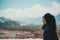 A beautiful Asian woman sitting , turn back and looking at a city , mountains , blue sky and green nature background