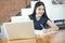 Beautiful Asian woman smiling and writing a notebook on table with laptop aside.