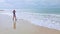 Beautiful asian woman walking along the white sand beach on sunny day with shadow reflection. Samed, Thailand.