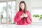 Beautiful Asian woman wearing pink sweater on white table smiling with hands on chest with closed eyes and grateful gesture on