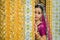 Beautiful Asian woman wearing a purple Indian traditional saree hides behind a beautiful pillar in a Buddhist temple