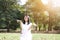 Beautiful asian woman in white dress smiling and sprinkle dry leaves in natural park. Thai girl or Chinese Girl enjoy on holiday