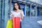 Beautiful asian young woman with shopping bags with smile while standing at the clothing store. Happiness, consumerism, sale and