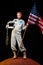 beautiful astronaut in spacesuit holding helmet and american flag on red