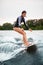 Beautiful athlete woman in swimsuit stands on a surfboard and rides on splashing wave