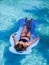 Beautiful athletic sun tanned girl floating on a pool float in a swimming pool on vacation