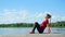 Beautiful, athletic young blond woman doing coordination and balance exercises , push-ups, swings press. Lake, river