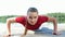 Beautiful, athletic young blond woman stretching, doing push-ups. Lake, river, blue sky and forest in the background