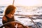 Beautiful attractive curly blonde adult woman looking the ocean enjoying a trip and travel on sail boat - modern generation people