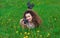 Beautiful, attractive girl-photographer with curly hair holds a camera and lying on the grass with blooming dandelions