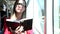 Beautiful attractive young woman holding book sitting in tram, looking at camera