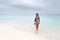 Beautiful Aussie woman walking along white sandy beach