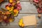 Beautiful autumn composition: a decorative wreath of dry bright yellow and red leaves, a sheet of craft paper, a pencil on a woode