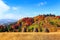 Beautiful autumn landscape with the green fair trees, orange coloured forest, high mountains and blue sky.