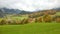 Beautiful autumn scenary between green fields and autumn trees leading to a farmhouse on a beautiful hillside