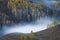 Beautiful autumn scene with a birch forest and fog throughout the valleys