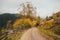 Beautiful autumn scenery in the mountains with wooden fence and dirt road. Carpathian Mountains