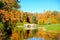 Beautiful autumn sunny landscape with the bridge over Slavyanka river and trees with red and orange leaves, Pavlovsk, St