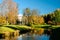 Beautiful autumn sunny landscape in Pavlovsk park with the Slavyanka river, orange leaves and the Temple of Friendship behind the