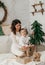 Beautiful baby boy near a Christmas tree with gifts