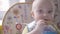 Beautiful baby boy at the table take a cookie in his hand, eating it, watching into the camera and babbling close up