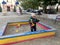 Beautiful baby in child sandpit posing photographer near sandbox