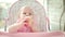 Beautiful baby eating apple in baby chair. Cute child tasting fruit