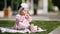 Beautiful baby-girl seating on the green grass and eating bake in the park.