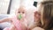 Beautiful baby girl sitting in mother embrace. Toddler girl with toy in mouth