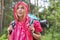 Beautiful backpacker in raincoat looking away at forest