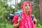 Beautiful backpacker in raincoat looking away at forest