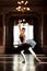 Beautiful ballerina dancing in a hall with a chandelier against the window
