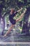 Beautiful ballerina girl in casual clothes posing on a blurred background of the park trees on background feet closeup