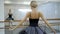 Beautiful ballet dancer is turning with body in ballet school indoors.