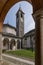 The beautiful baptistery and the bell tower of Baveno, Italy, framed by the columns of the portico of the via crucis