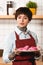 Beautiful barista in apron holding dish with tasty cookies.