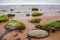A beautiful beach landscape with a green moss covered stones. Algae growing on seaside rocks.