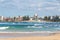 Beautiful beach with mild waves and cityscape on the background